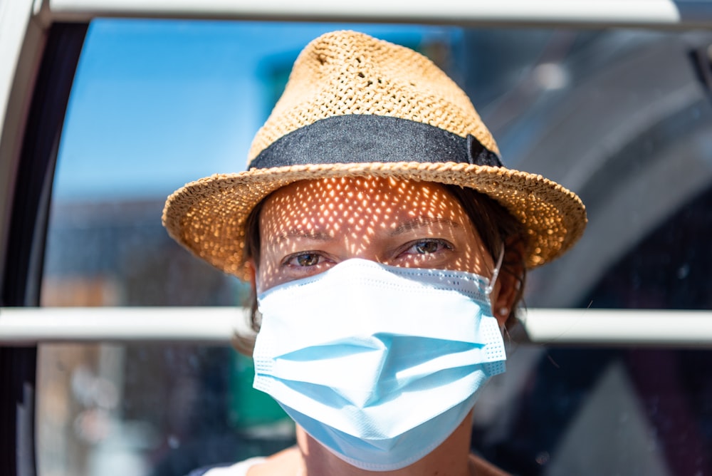 woman in brown hat with white face mask
