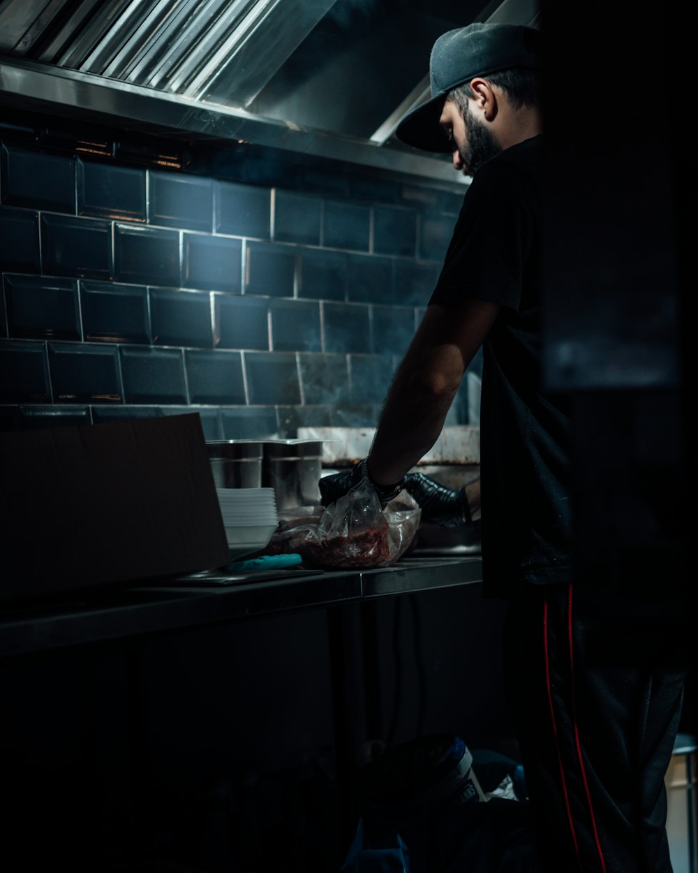 man in black t-shirt standing in front of table