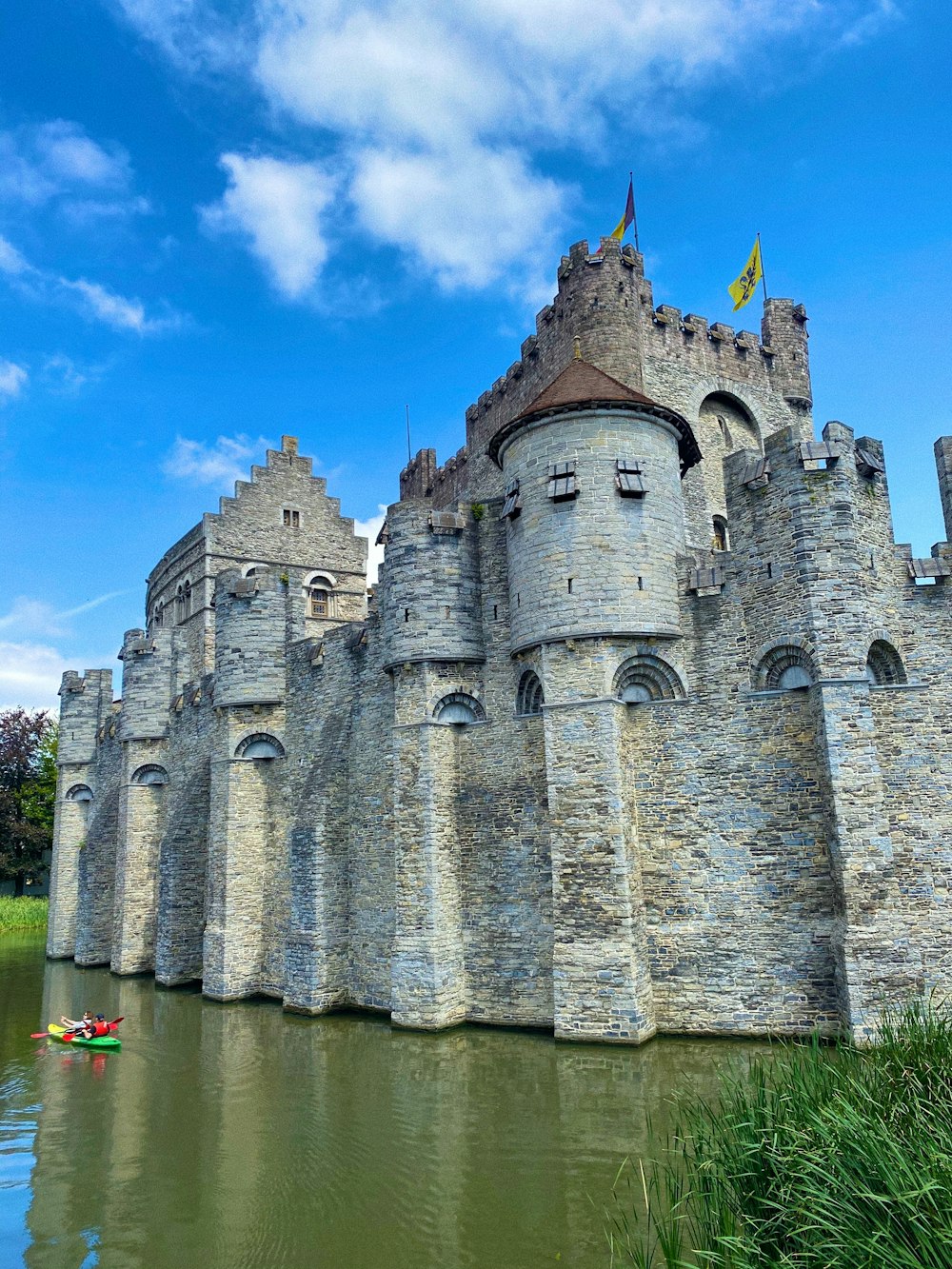grey concrete castle near body of water under blue sky during daytime