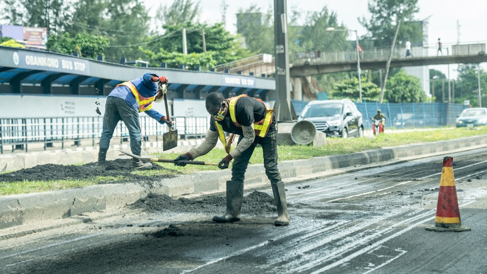 Hombre con chaqueta azul y amarilla y pantalones negros caminando por la carretera durante el día