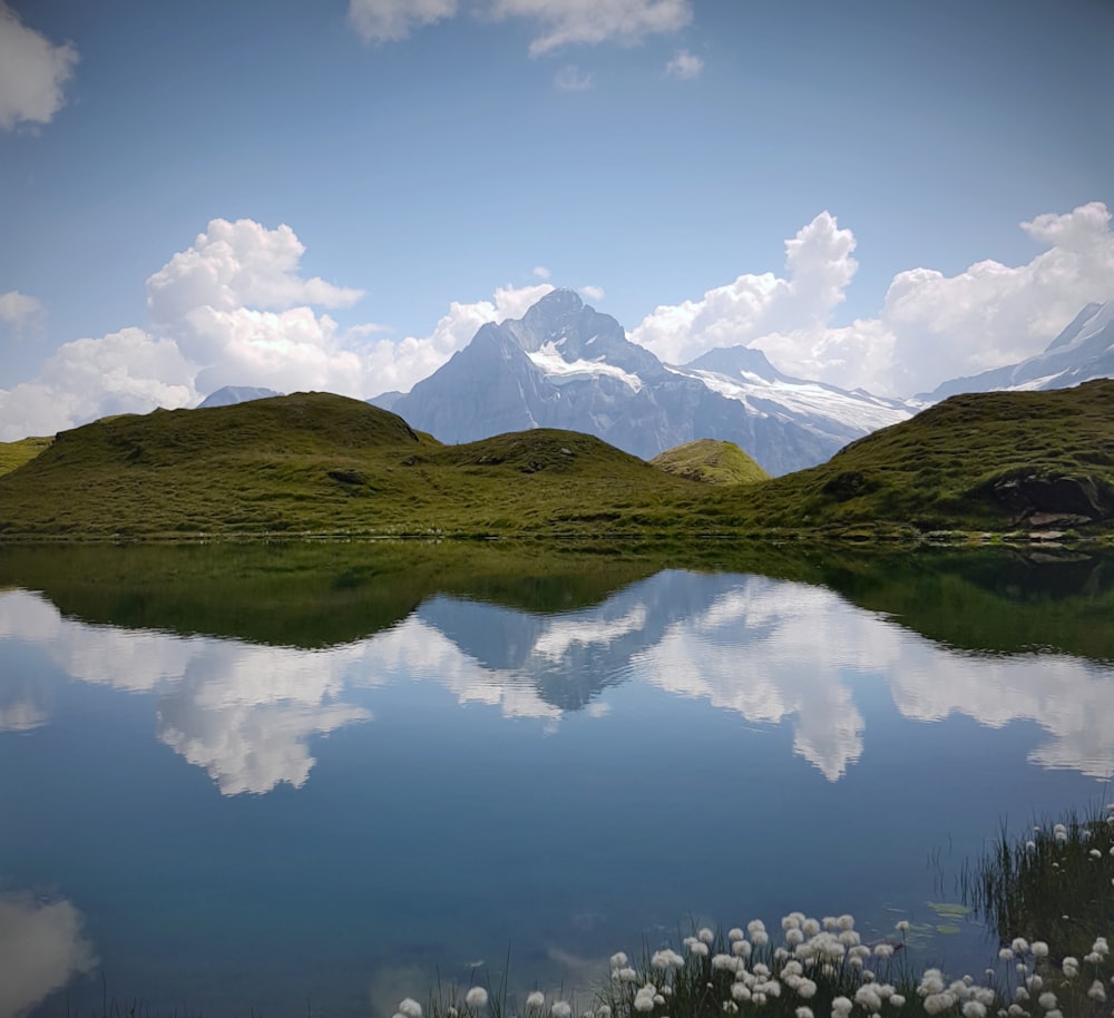 green and brown mountains beside lake under blue sky and white clouds during daytime