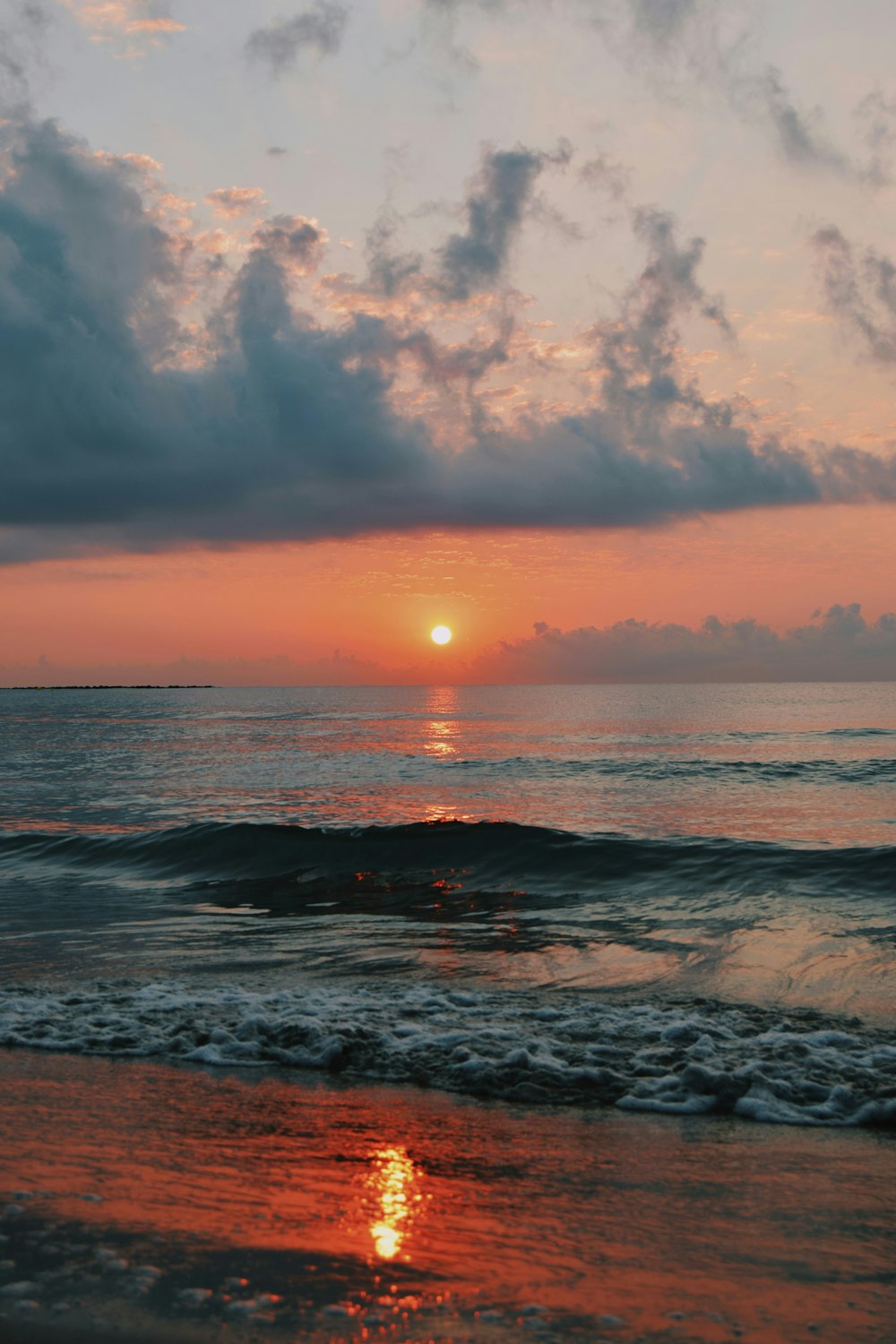 ocean waves crashing on shore during sunset