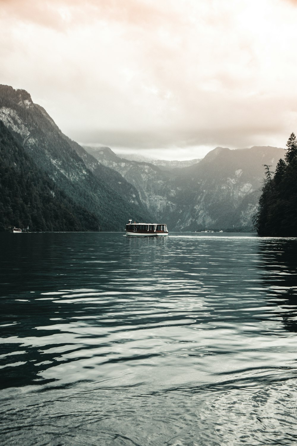 white boat on lake near green mountains during daytime
