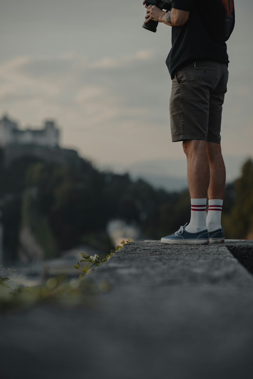 Person in schwarzen Shorts und weißen und schwarzen Nike-Turnschuhen, die auf grauem Betonpflaster stehen während