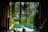 A tranquil setting featuring a lush, green environment with cascading plants and a reflection pool. Sunlight filters through the foliage, creating a serene, inviting atmosphere within a partially open, architectural structure.