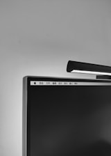 A close-up view of a computer monitor with a light bar mounted on its top edge. The screen is off, displaying a minimalistic interface with menu items in a different language. The setting appears to be a controlled environment with a plain background.