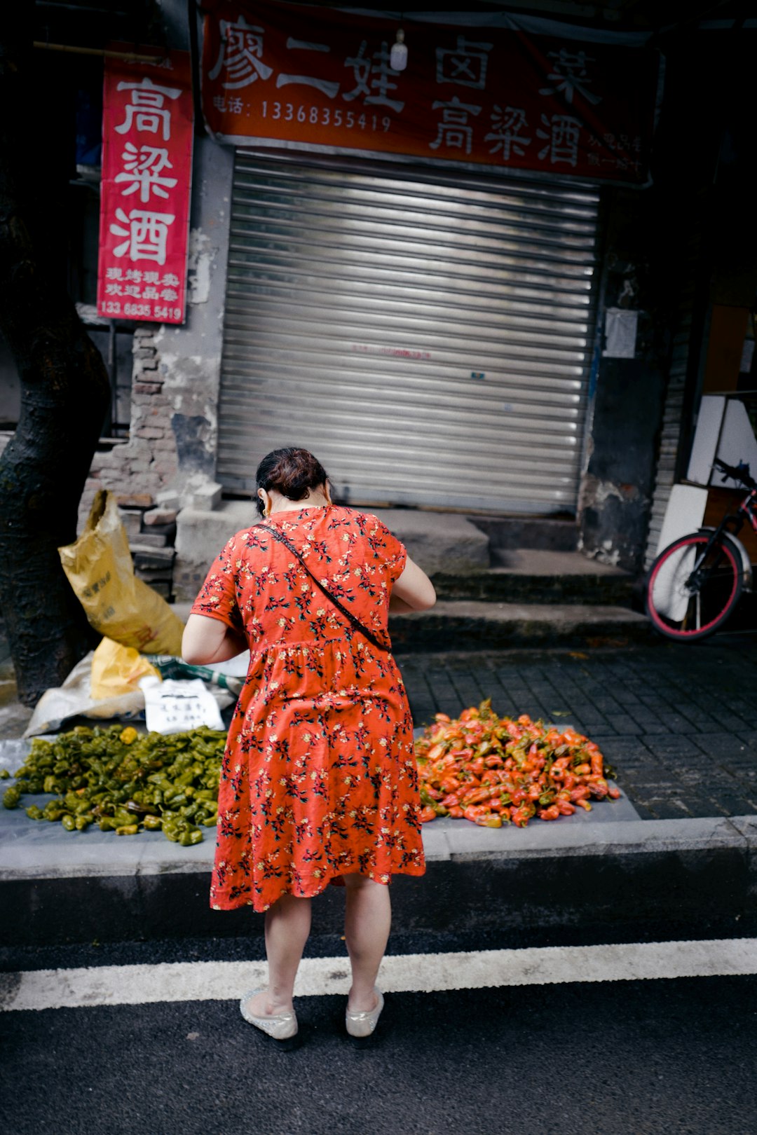 woman in orange and white floral sleeveless dress standing beside gray steel roll up door during