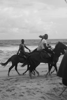 Local Sumbanese horsemen riding along the coastline with the ocean waves in the background.