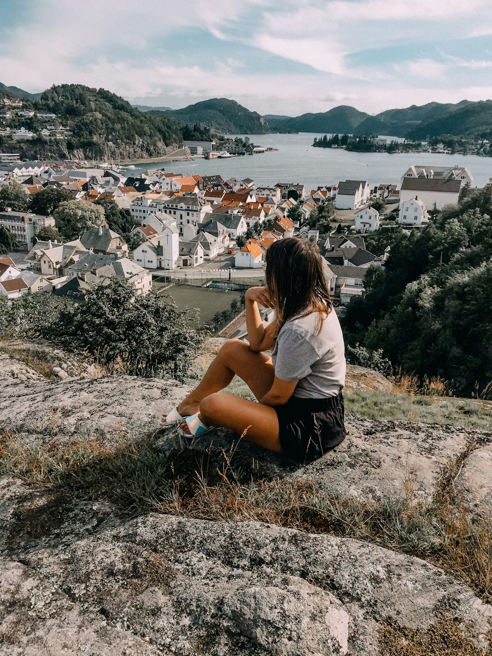 woman in white t-shirt sitting on brown rock during daytime