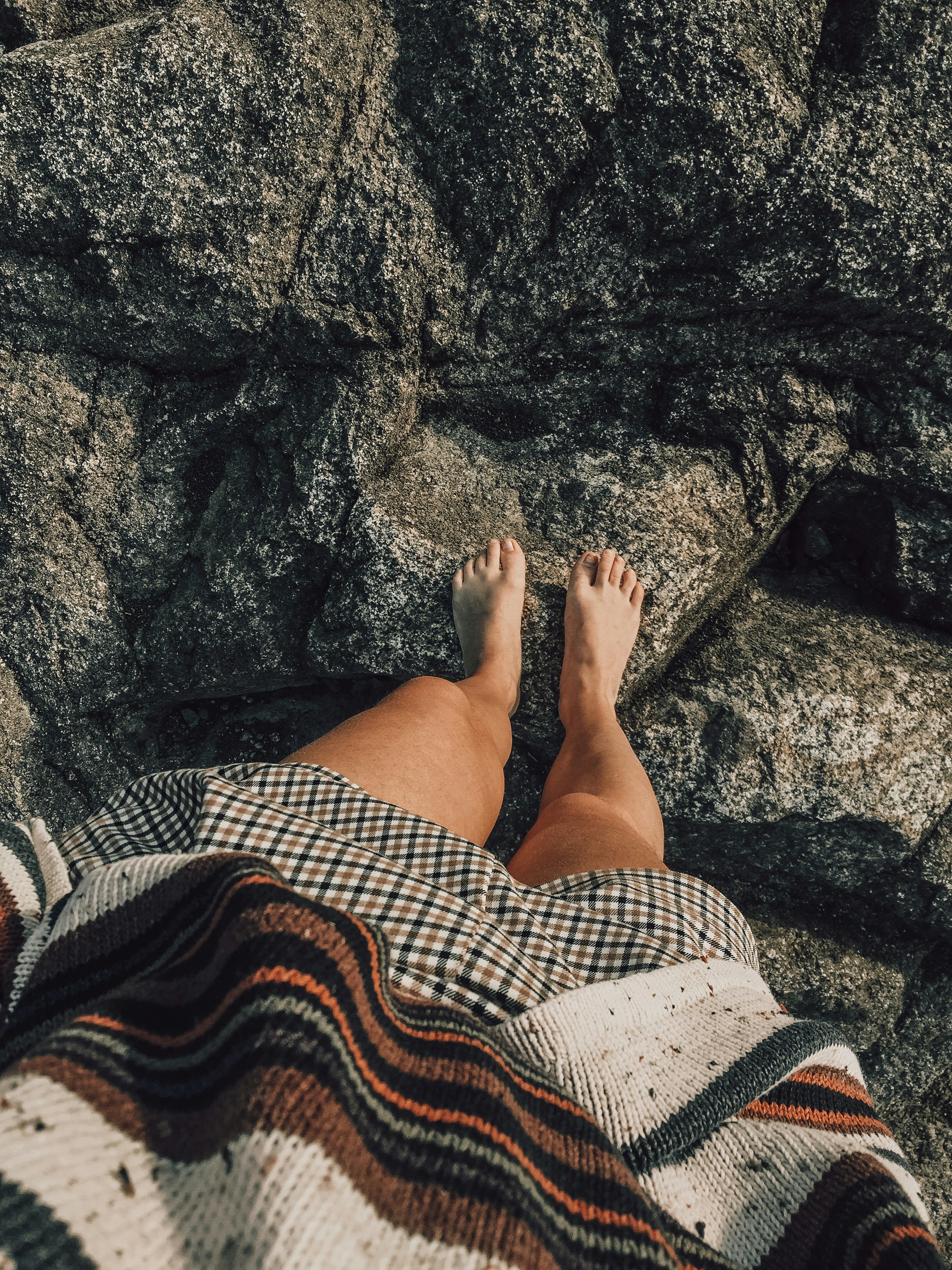 woman in white and black skirt sitting on rocky ground