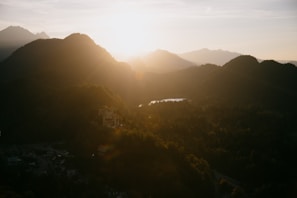 A panoramic view of a fantasy game landscape with mountains and castles under a sunset.