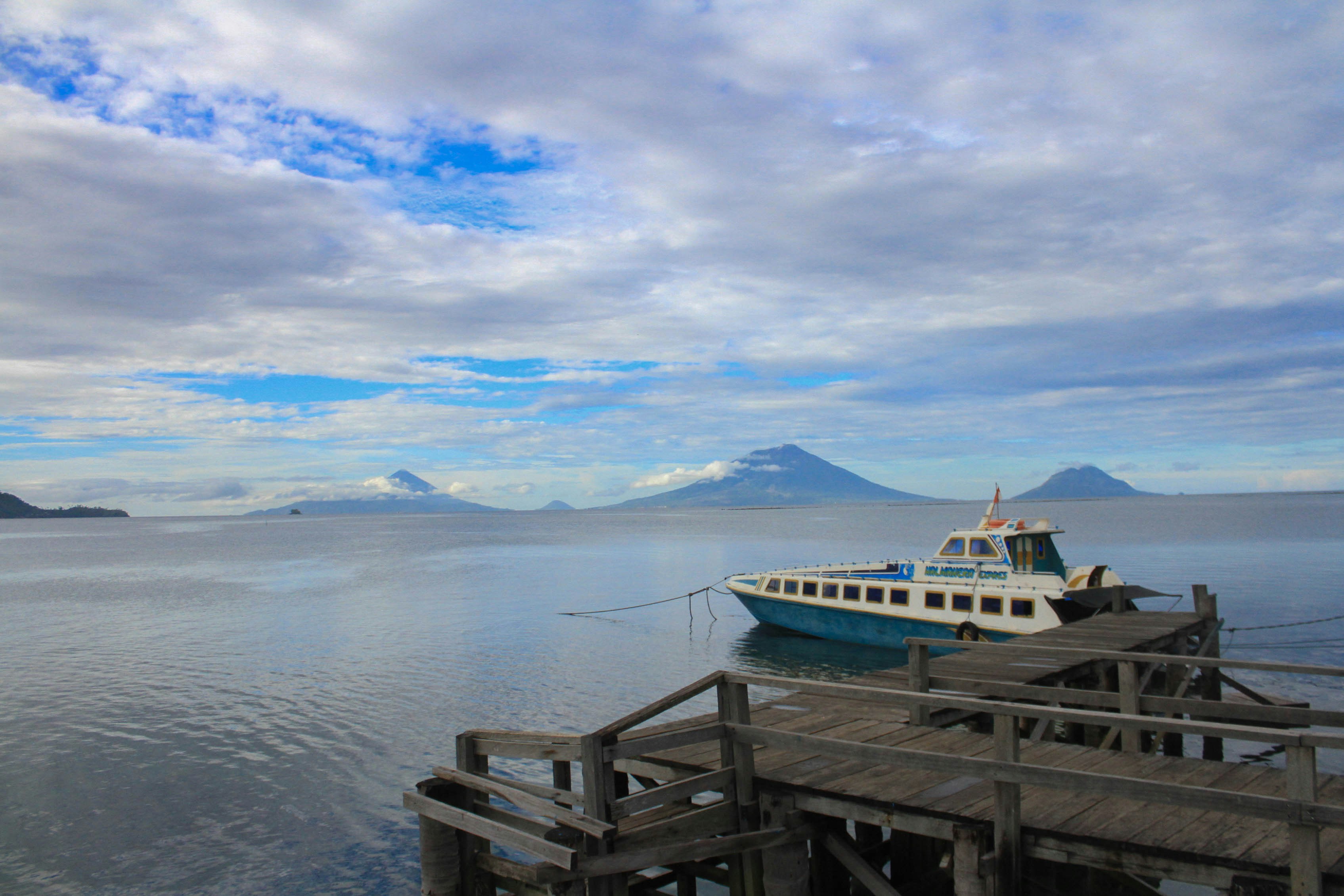 white and blue boat on sea under cloudy sky during daytime