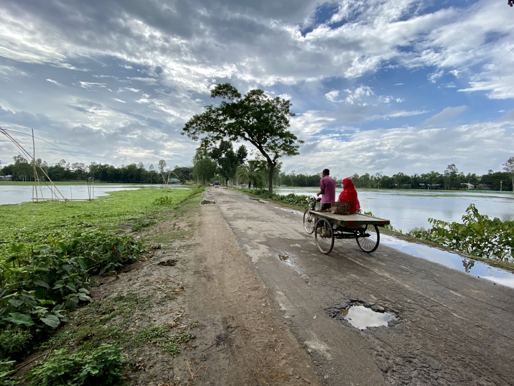 Hombre con camisa roja montando en bicicleta cerca del cuerpo de agua durante el día