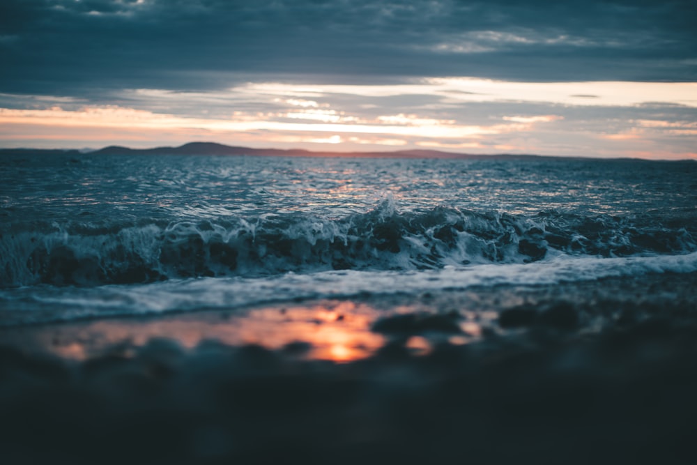 ocean waves crashing on shore during sunset