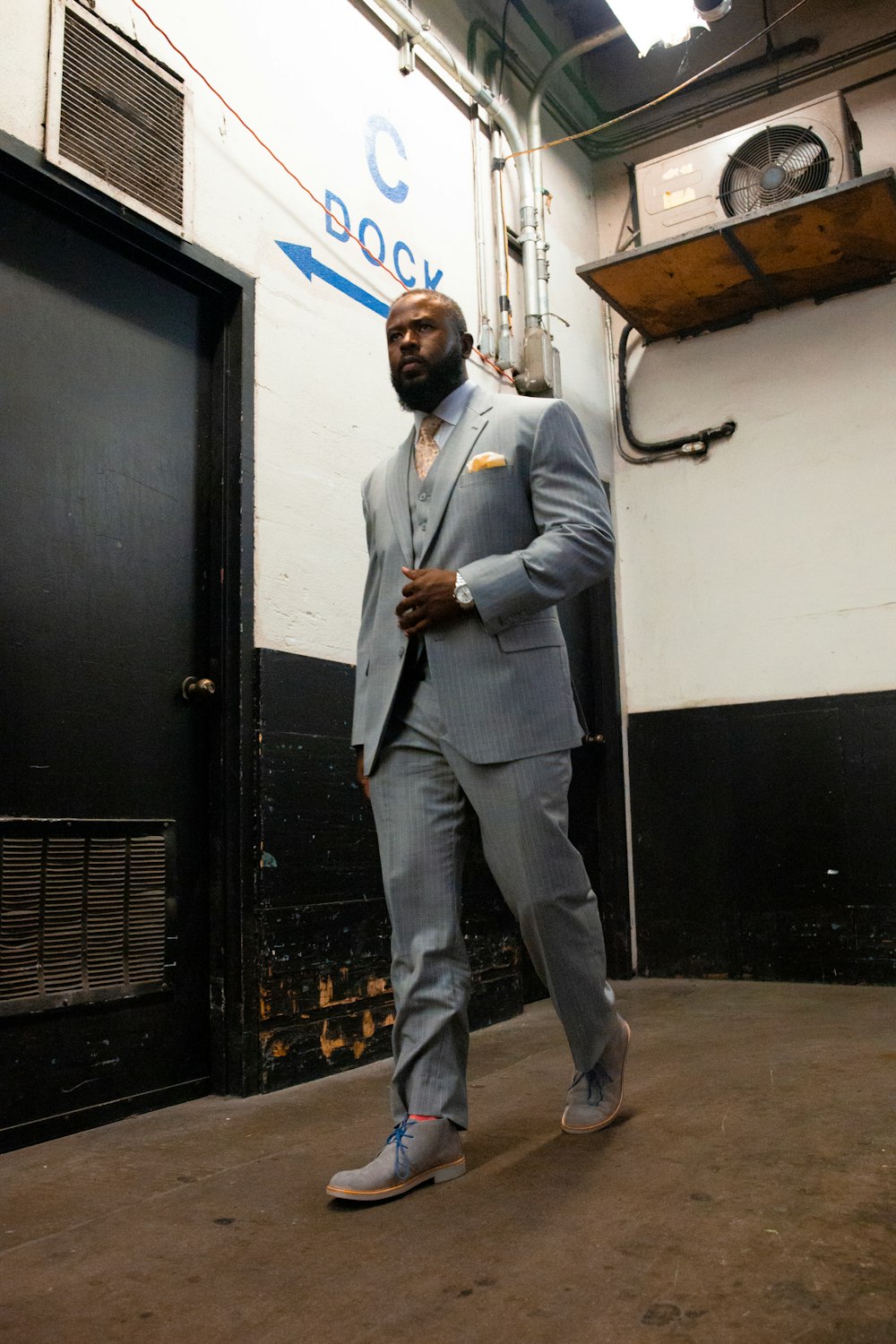 man in gray suit standing near black door