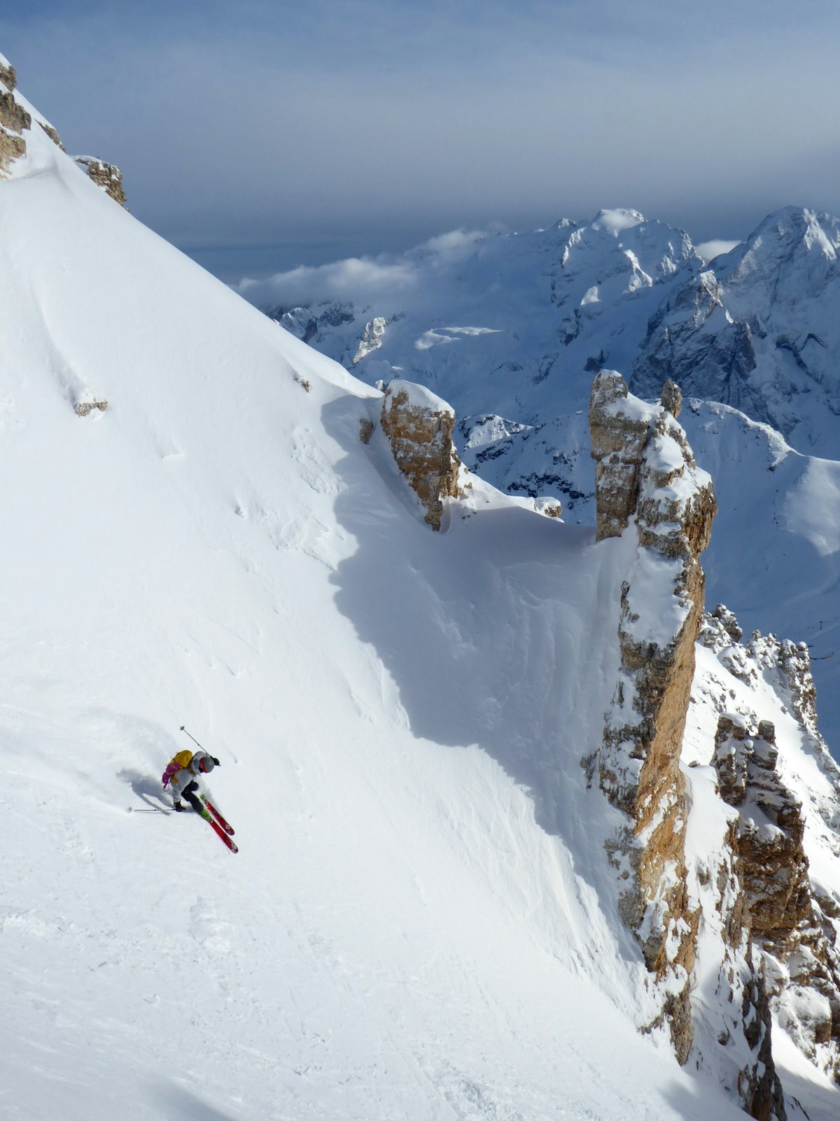 Sciatore in giacca rossa sulla neve in montagna durante una giornata di sole