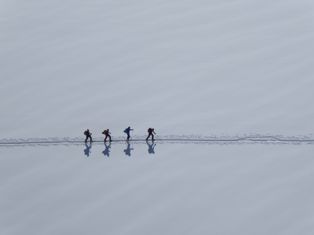 3 person in red shirt and black pants standing on snow covered ground during daytime