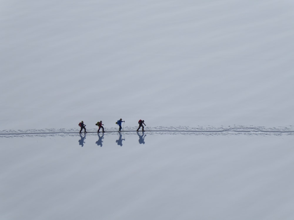 3 person in red shirt and black pants standing on snow covered ground during daytime