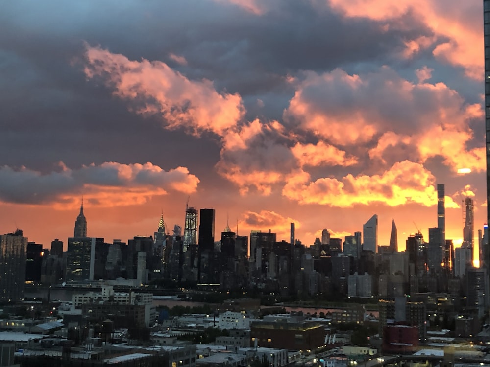 city skyline under orange and gray cloudy sky during sunset