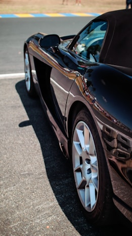 A shiny black car freshly detailed with gleaming reflections under the sun.