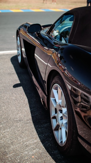 Close-up of a sleek black sports car with a flawless glossy finish under natural light.