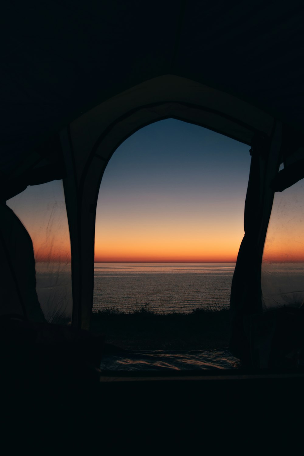 silhouette of person standing on seashore during sunset