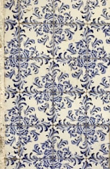 Blue and white ceramic tiles featuring ornate floral patterns with symmetrical designs. The tile arrangement is consistent and repeats across the surface, showcasing a traditional and decorative style.