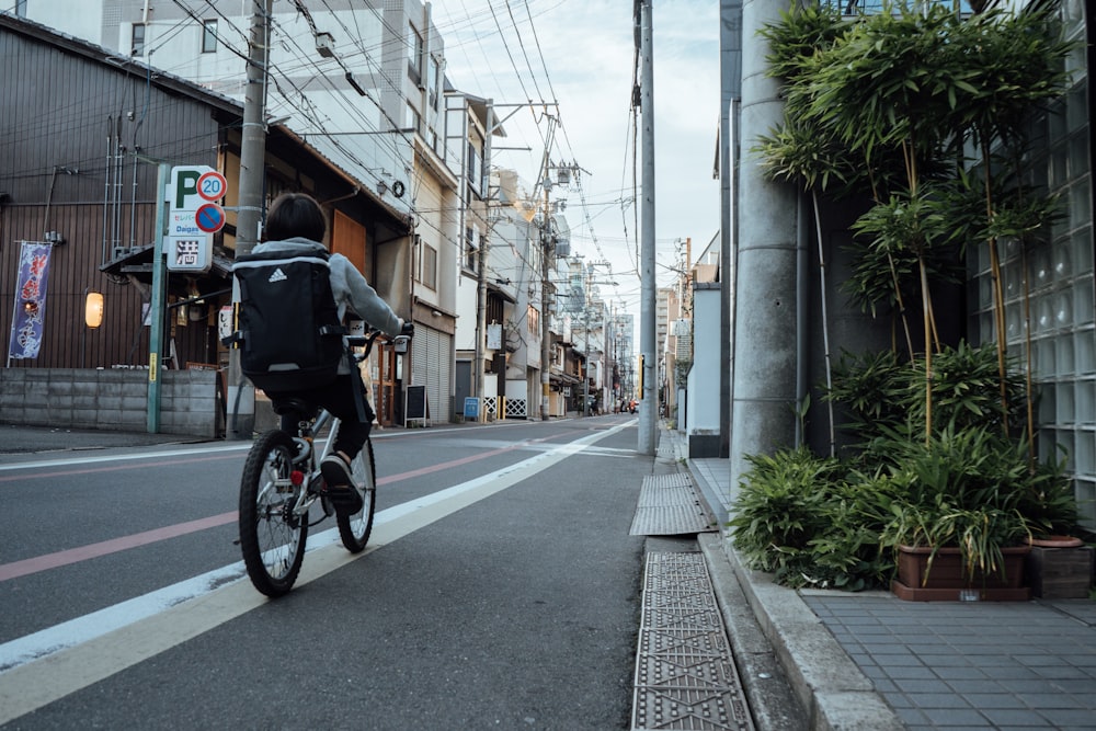 man in black jacket riding bicycle on road during daytime