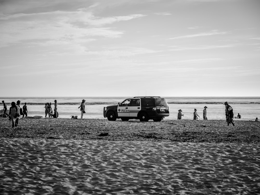 Foto en escala de grises de personas caminando por la playa
