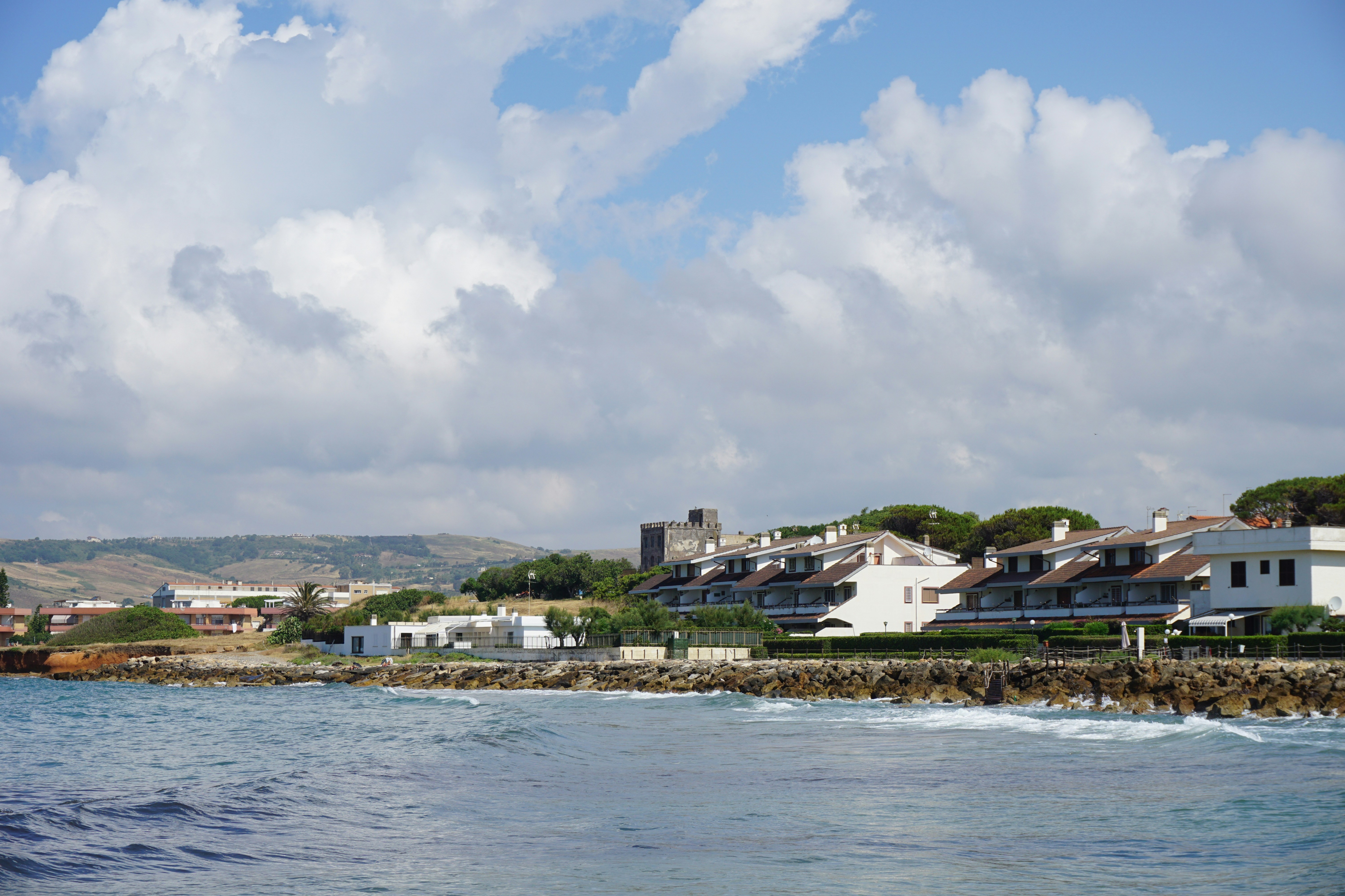 a large body of water with houses in the background, Quiet place beside the beach