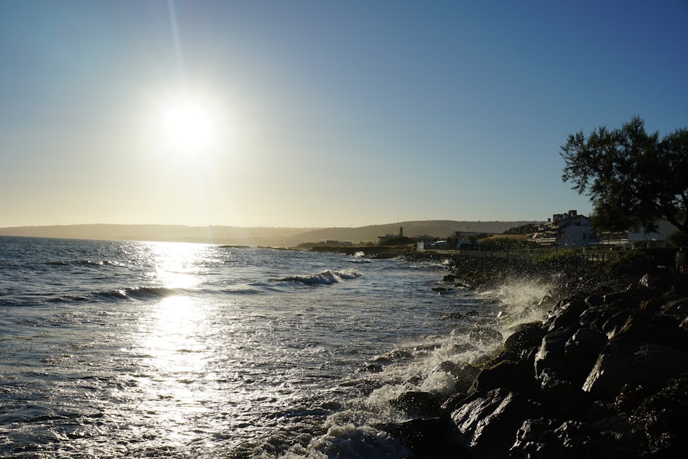 the sun is shining over the water and rocks