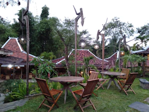 A serene outdoor classroom surrounded by lush greenery and traditional cultural decorations.