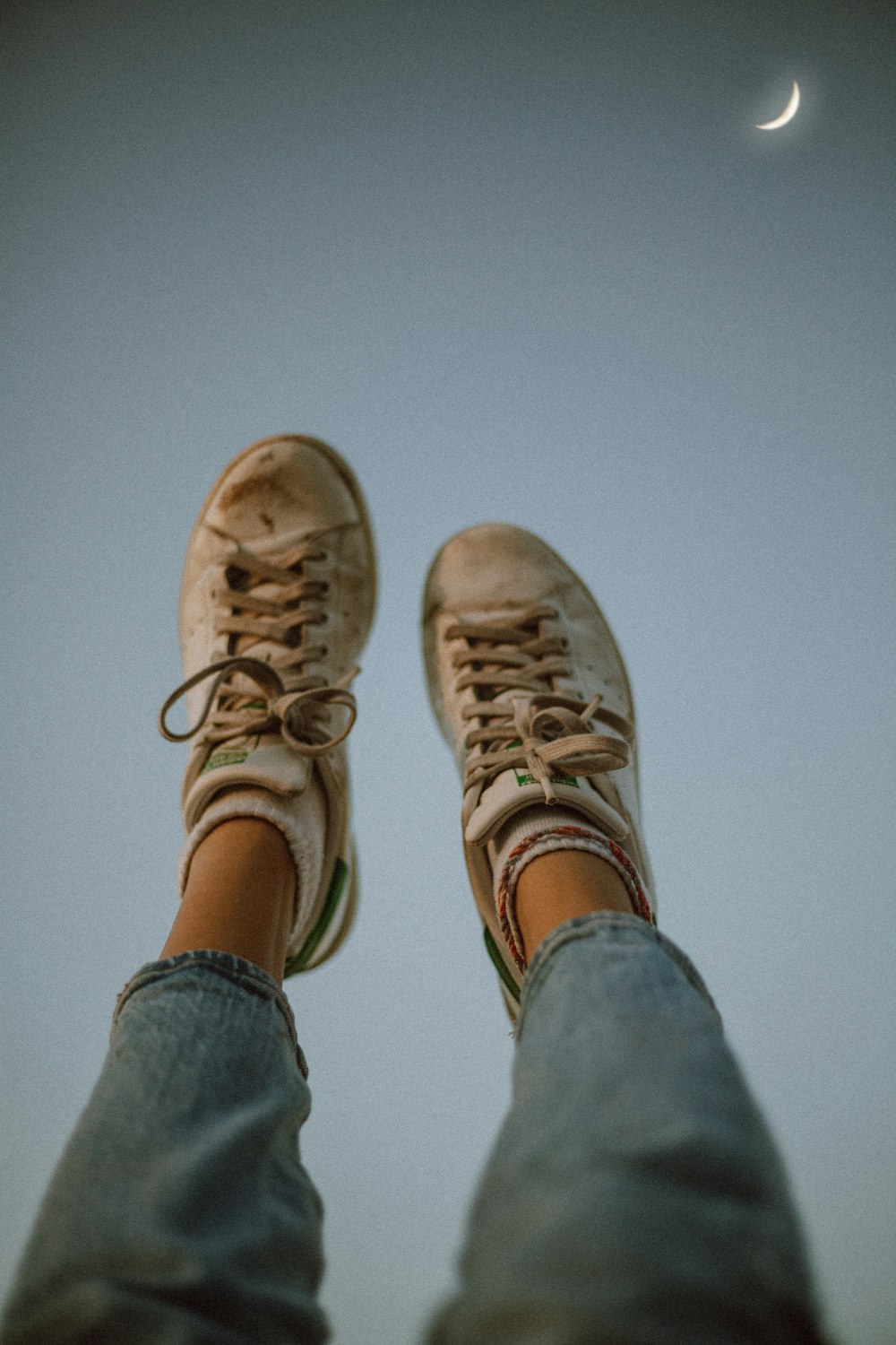 a person's feet with a half moon in the background