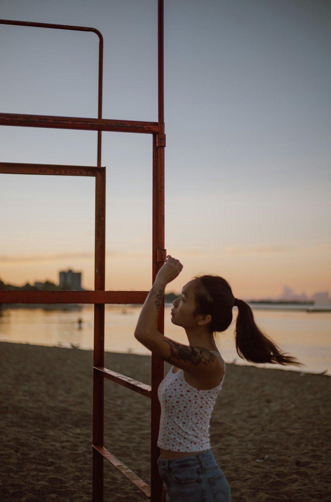 woman in white and blue floral tank top leaning on brown wooden railings during sunset