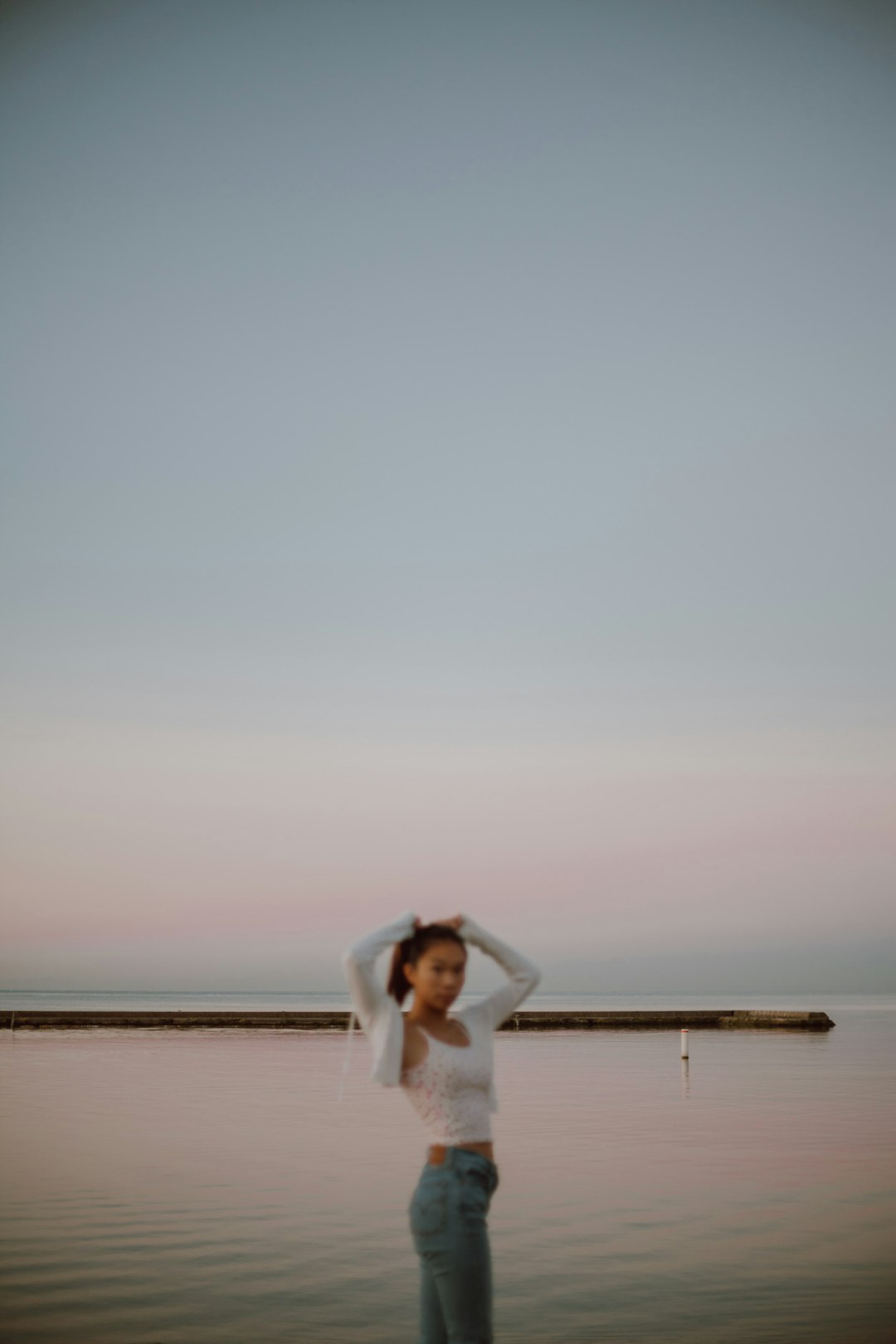 woman in white long sleeve dress standing on brown wooden dock during daytime