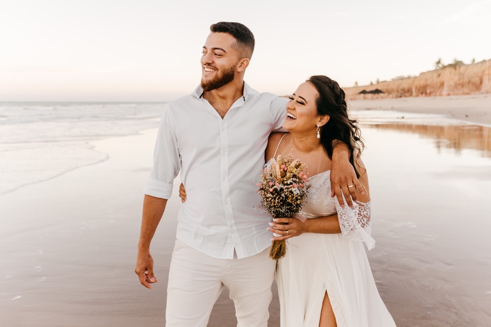 man in white button up shirt and white pants holding woman in white dress