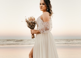 woman in white dress holding bouquet of flowers