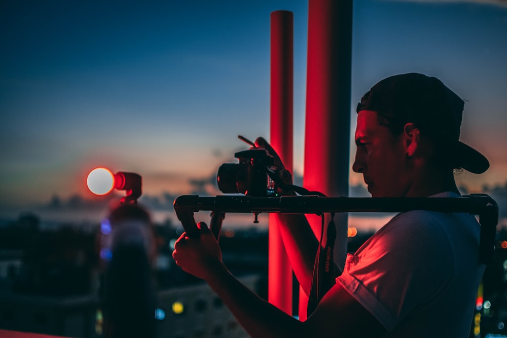 man in red shirt holding black camera during sunset