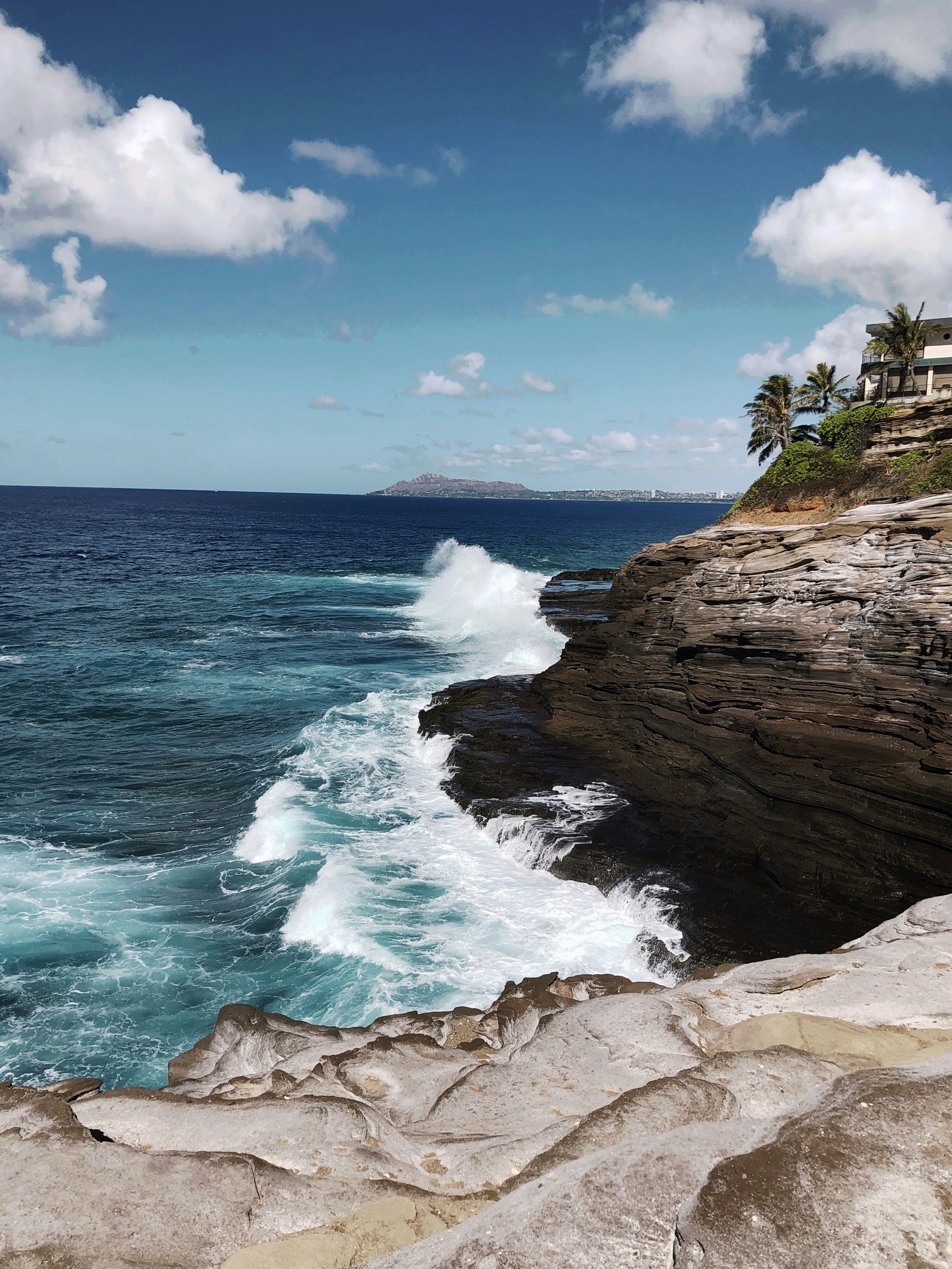 brown rock formation near sea under blue sky during daytime