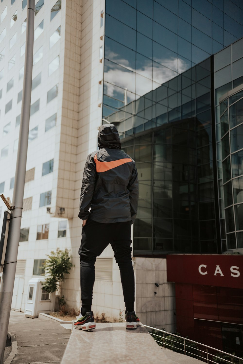 man in black jacket and black pants standing in front of building during daytime