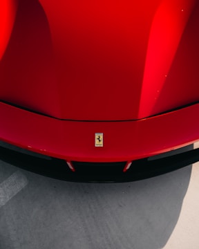 red ferrari car on gray concrete floor