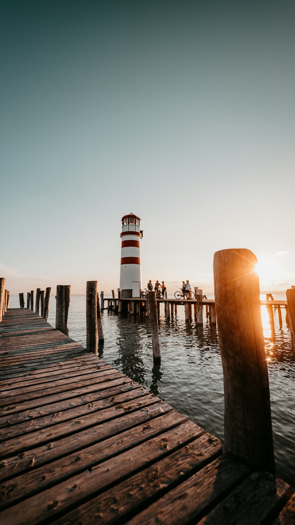 brown wooden dock on body of water during sunset