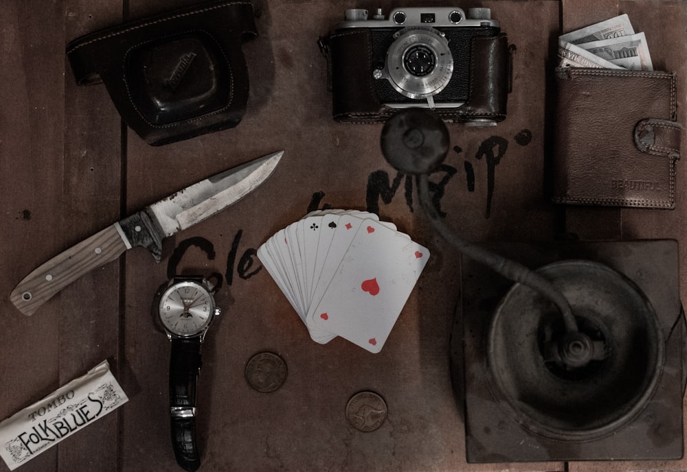 black and silver camera beside white textile and black handled knife