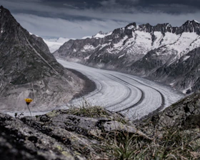 person in yellow jacket walking on road near snow covered mountain during daytime