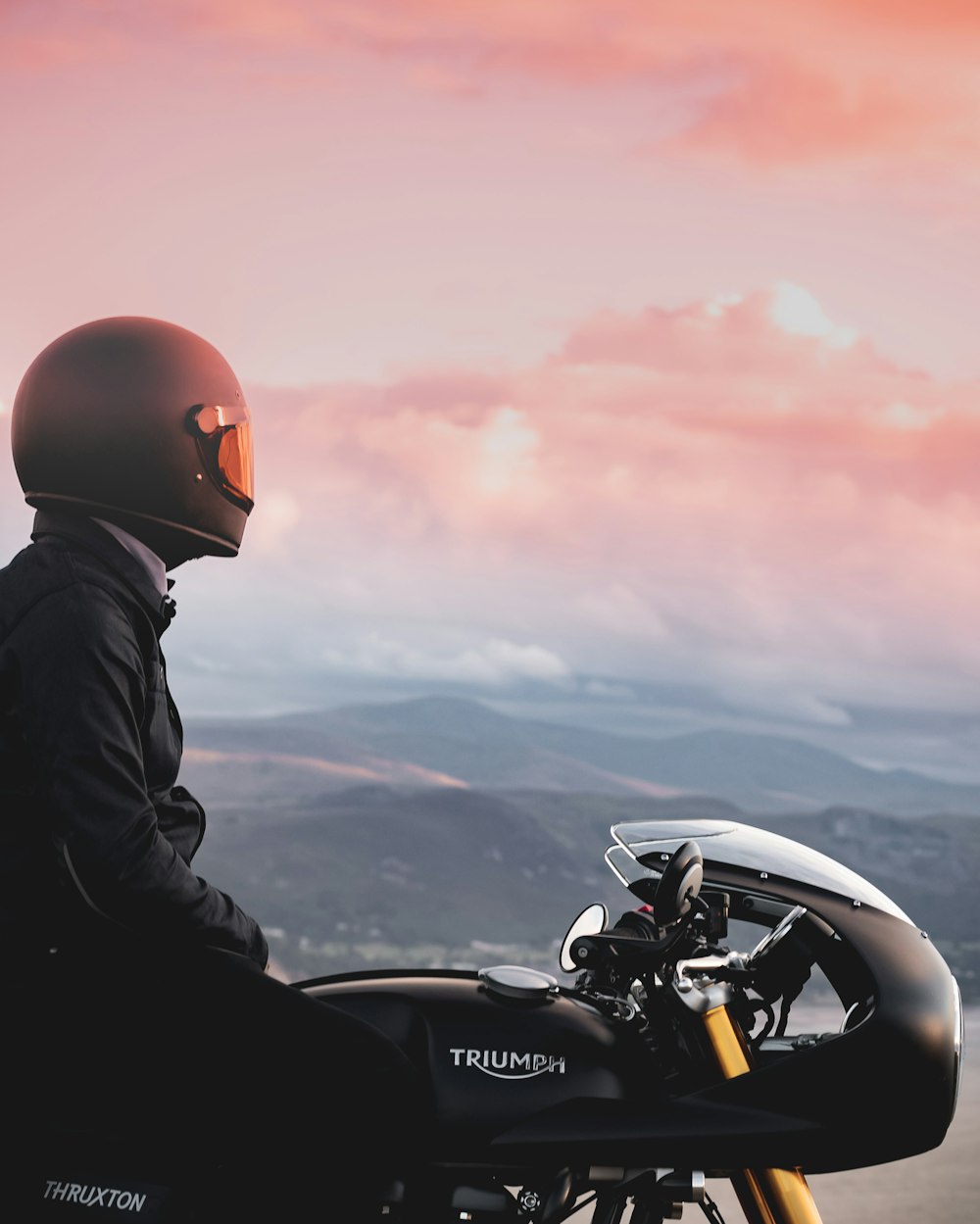 man in black jacket and orange helmet riding black motorcycle