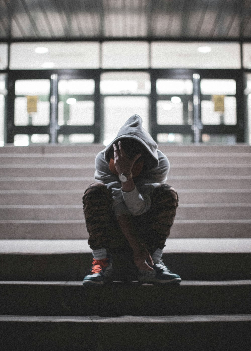 person in gray hoodie sitting on stairs