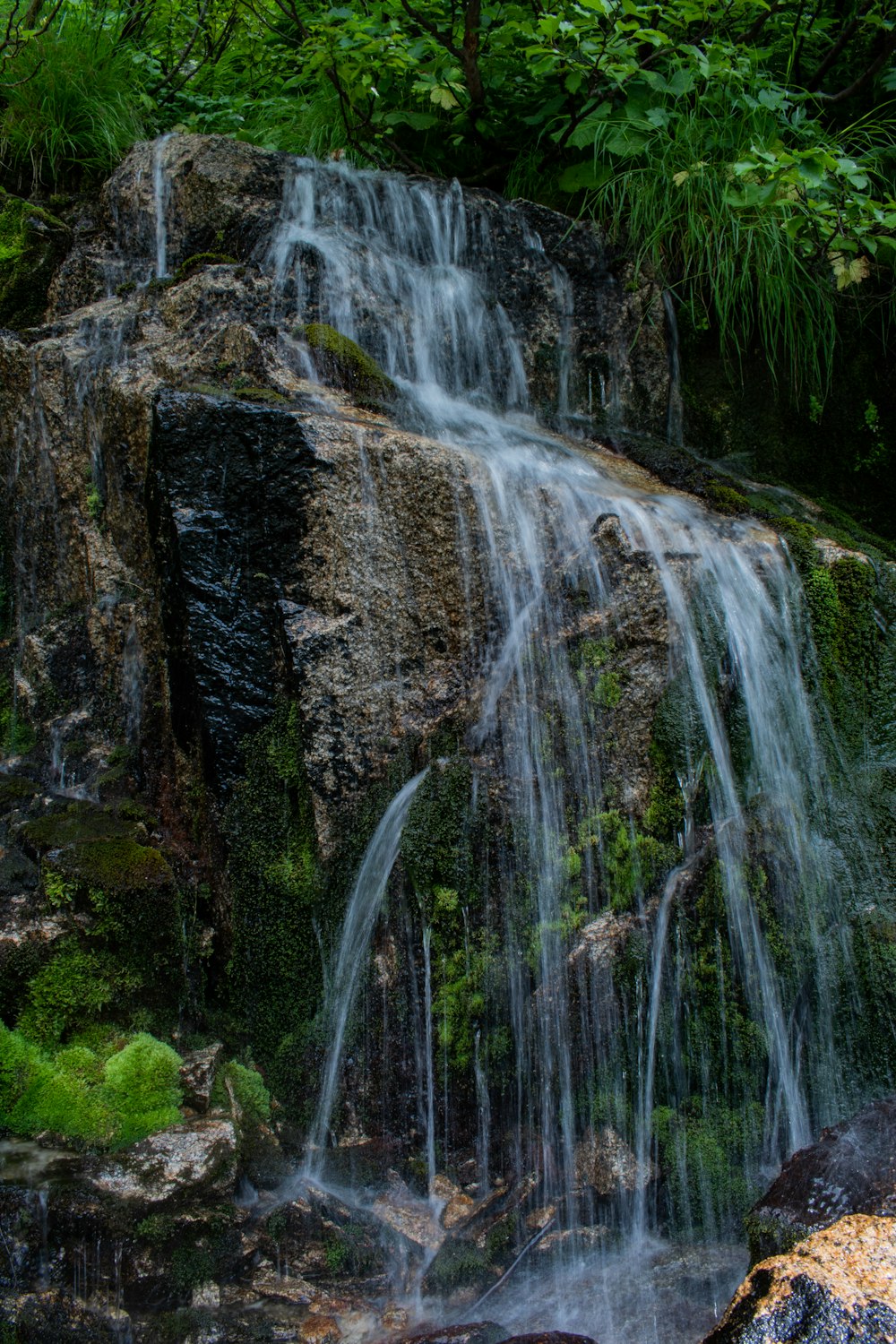 water falls on brown rocky mountain