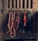 A collection of horse tack, including bridles and ropes, hangs neatly from hooks on a wooden wall. Each item varies in color and texture, with some made of leather and others of rope.