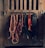 A collection of horse tack, including bridles and ropes, hangs neatly from hooks on a wooden wall. Each item varies in color and texture, with some made of leather and others of rope.