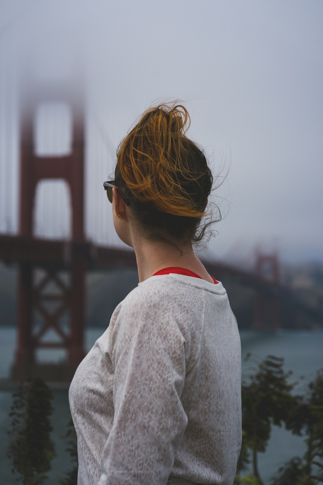 woman in white long sleeve shirt wearing black sunglasses standing near body of water during daytime